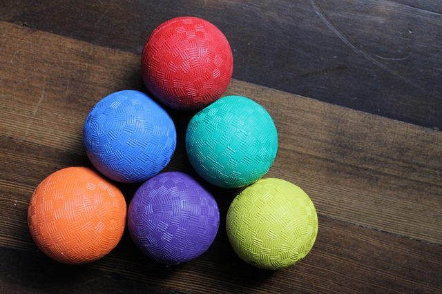 Colorful textured balls arranged in pyramid shape on wooden floor.