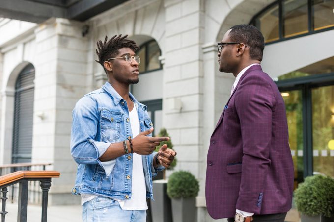 two young and stylish African American men in the city smiling and talking. father and adult son relationship
