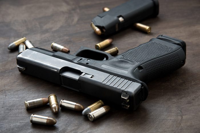 Gun with ammunition on wooden background.
