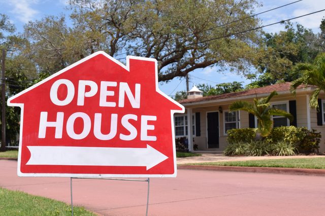 Sign reading "Open House" points right, outside a suburban home surrounded by trees and grass.