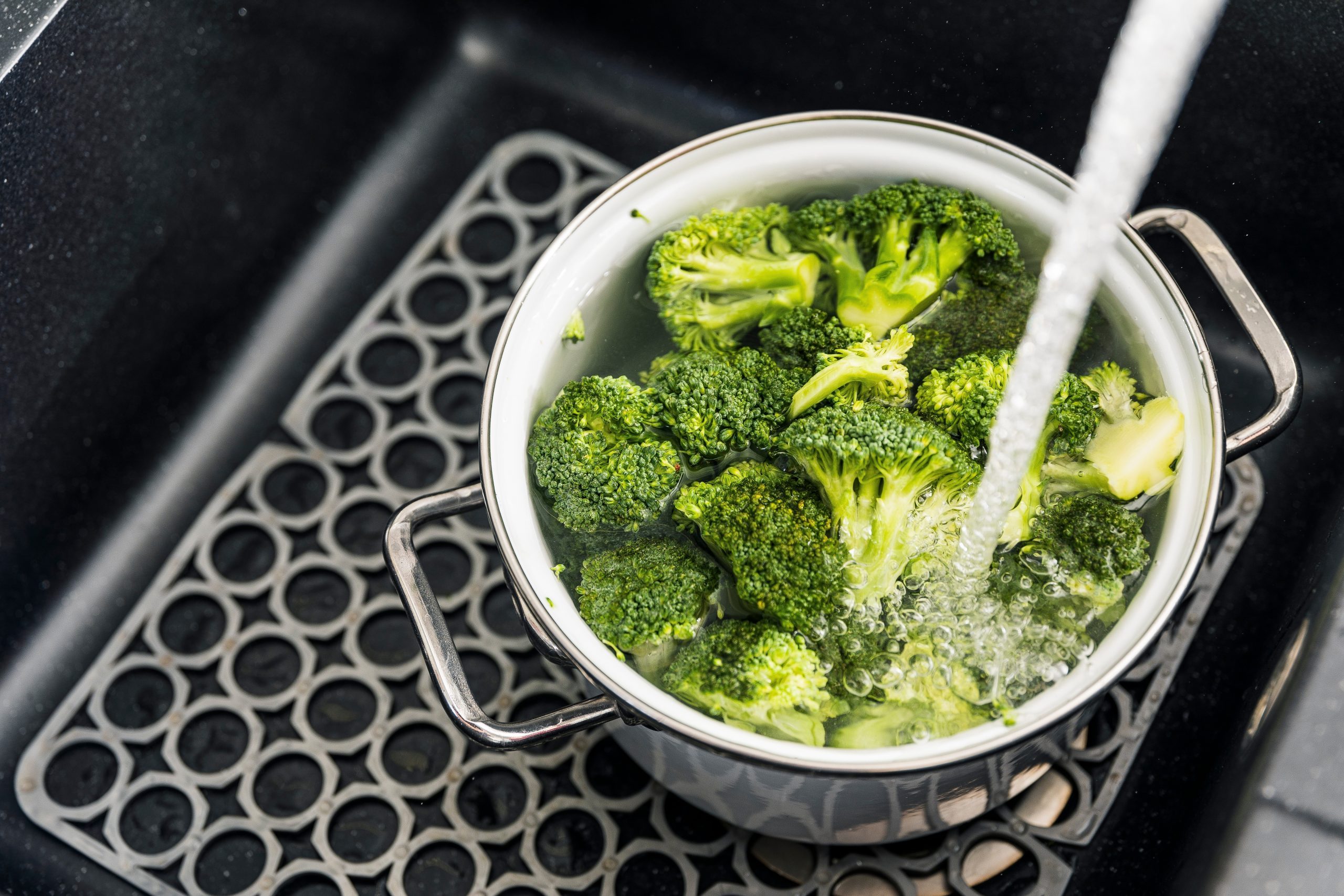 Woman washes vegetables and fruits under running water. Preparing food ingredient for lunch