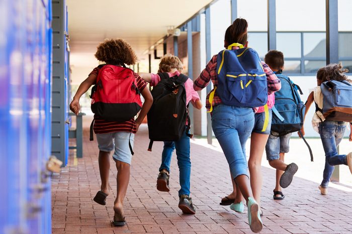 School kids running in elementary school hallway, back view