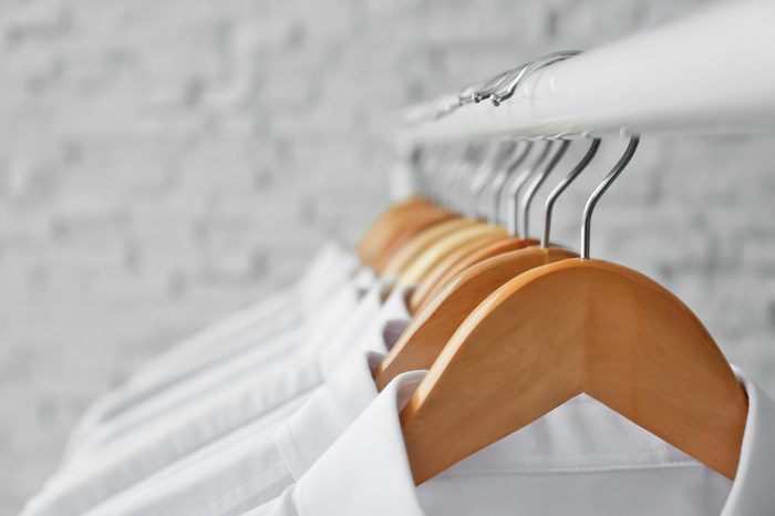 Rack with clean clothes on hangers after dry-cleaning, closeup