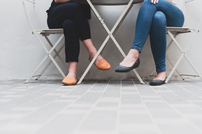 Lower legs of two women in relative friendship at outdoors office or restaurant. People and lifestyles concept.