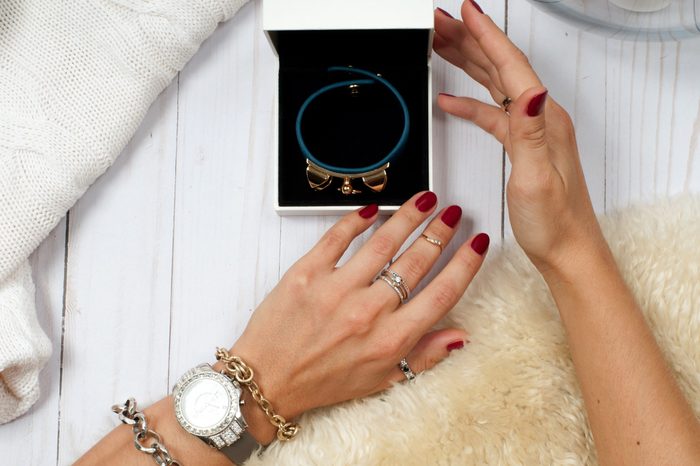 Female hands with jewelry and gift. Fashion accessories, wrist watches, glamor bracelets and rings