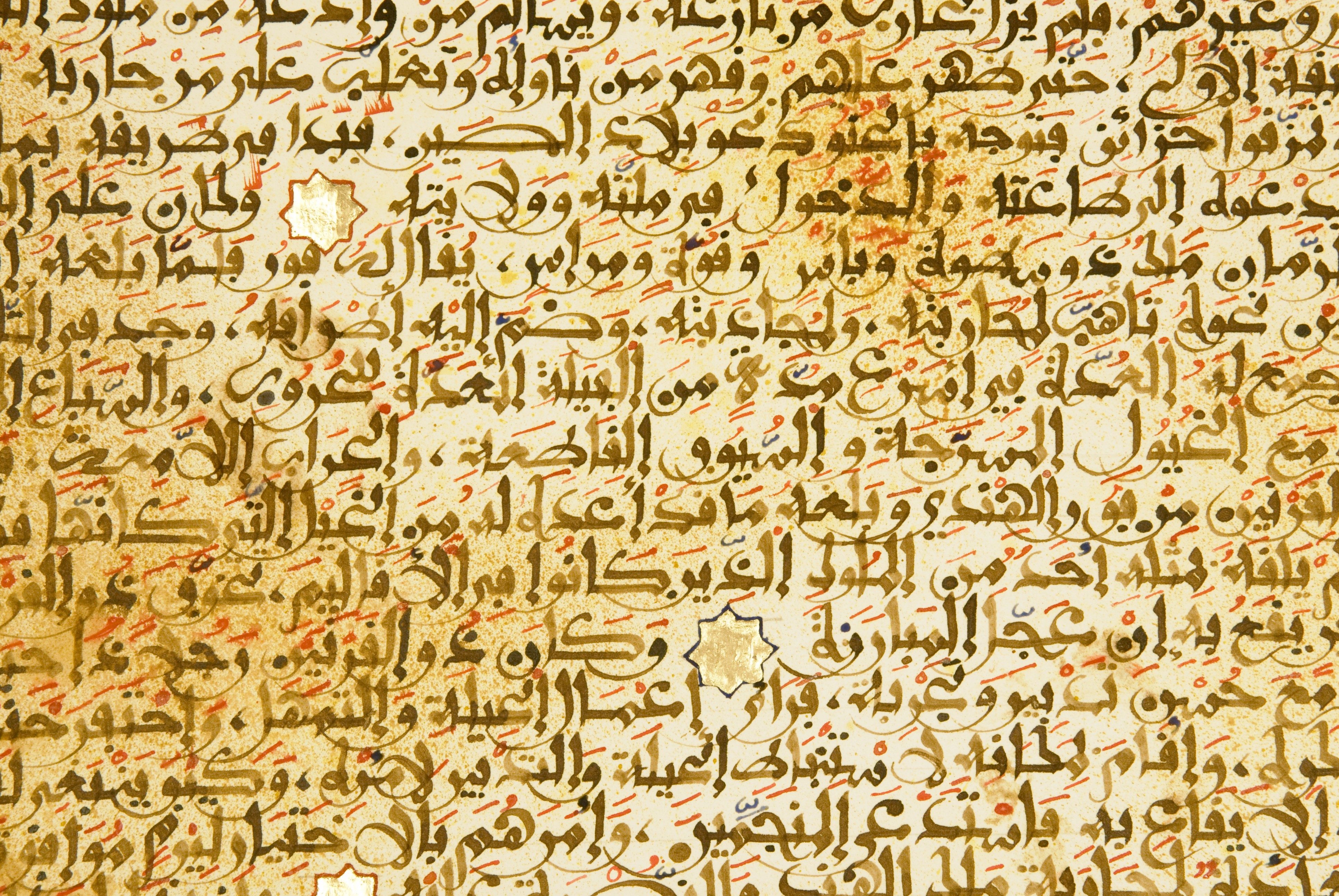 Intricate Arabic calligraphy fills the page, adorned with red diacritics and gold embellishments, creating a rich, historical manuscript appearance.