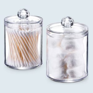 Two clear jars hold cotton swabs and cotton balls, sitting on a light-colored surface.