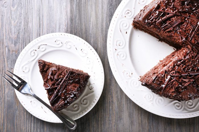 Sliced tasty chocolate cake on wooden table background