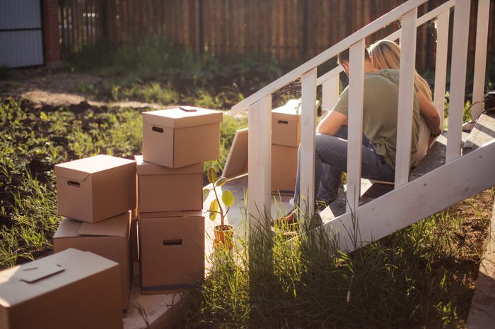 Family Outside House On Moving Day. cardboard boxes foreground near steps