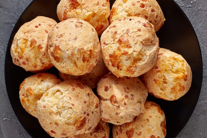 overhead view of Gougeres, cheese puffs balls on a black plate. Traditional french cheese choux buns on a concrete table, view from above, flatlay, close-up, copy space
