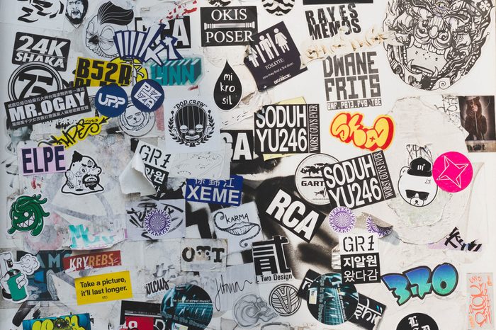 Street wall covered numerous multicolored stickers.