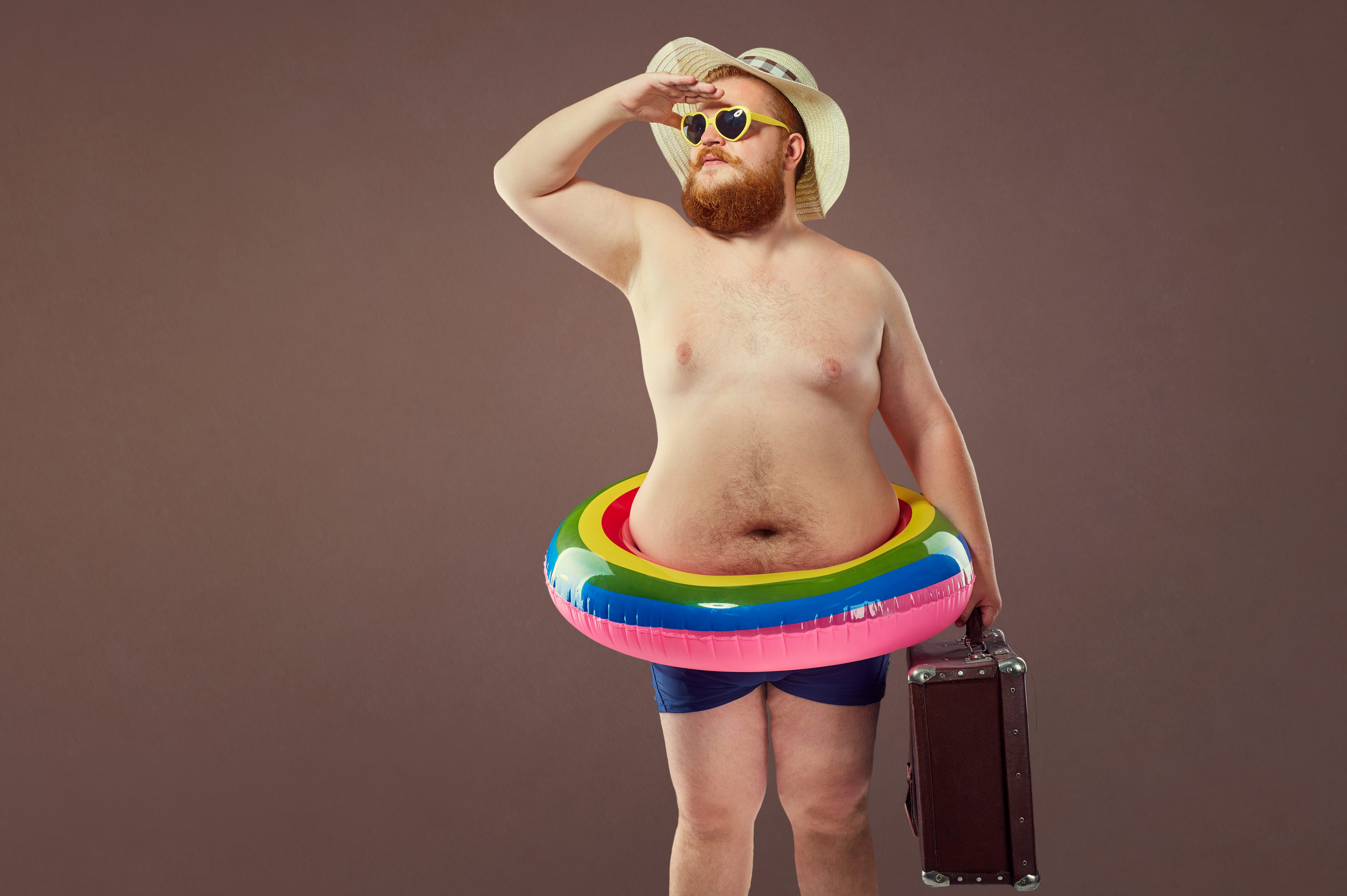 Funny fat bearded man with a suitcase in a hat and glasses on va