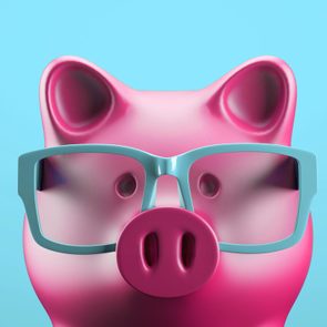 A pink piggy bank wears blue glasses against a solid light blue background.