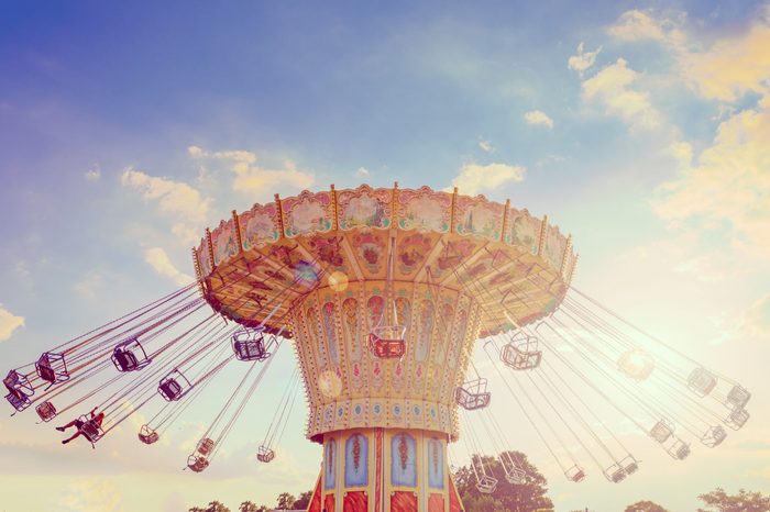 Wave Swinger ride against blue sky, vintage filter effects - a swinging carousel fair ride in amusement park at dusk