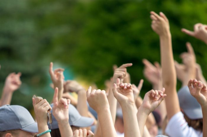 Group of happy young people with hands up to the sky over green natural background