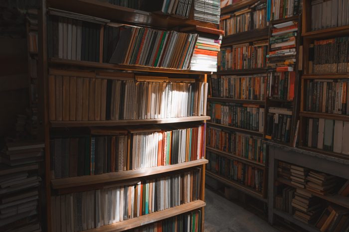 Old cozy library. Game of light and shadow on shelves with books in the library. Background Library