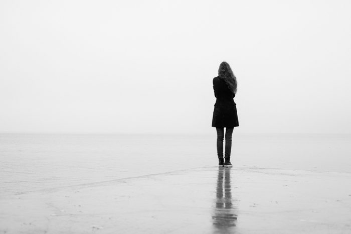 A lonely girl looks out into the distance in the rain. Black and white. Loneliness