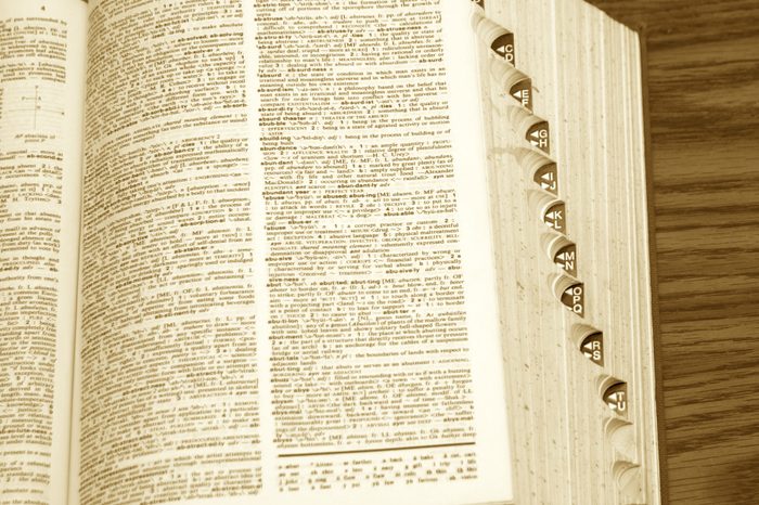 old dictionary with page open, showing side tabs on desk in sepia