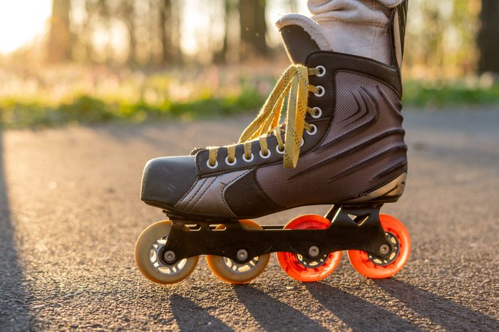 Close view of inline skates. Outdoor inline skating on smooth concrete ground. Ice skating at sunset. Background with bokeh