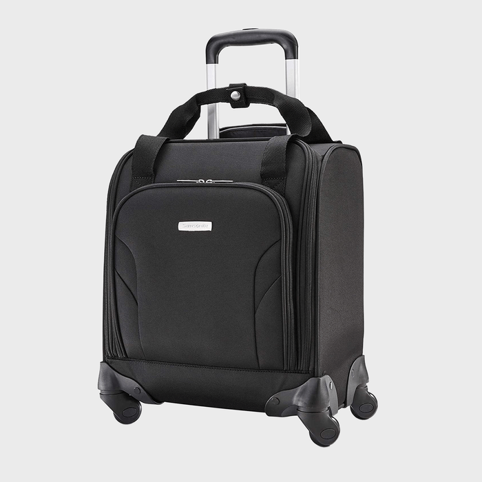 A black carry-on suitcase stands upright with a retractable handle and four wheels, set against a light gray background.