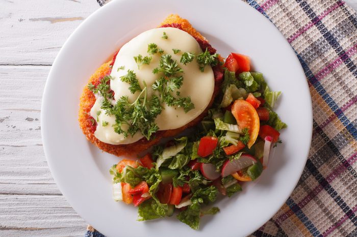 Italian chicken Parmigiana and fresh vegetable salad close up on a plate on the table. horizontaltop view