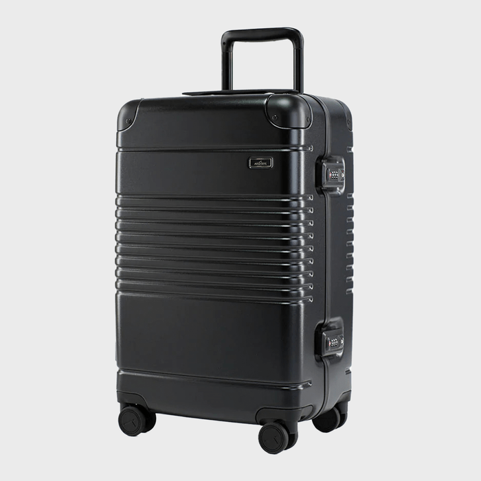 A black wheeled suitcase stands on a plain background, featuring a textured design and a retractable handle.
