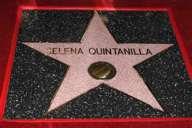 Star plaque inlaid in black-speckled terrazzo, reading "SELENA QUINTANILLA," set on a red carpet background.