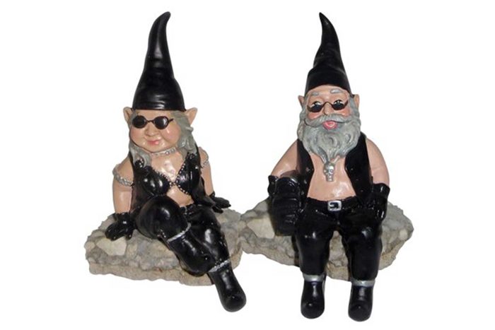 Gnomes sit on rocks wearing black leather outfits, sunglasses, and spiky hats, appearing relaxed and playful in a quirky, lighthearted setting.