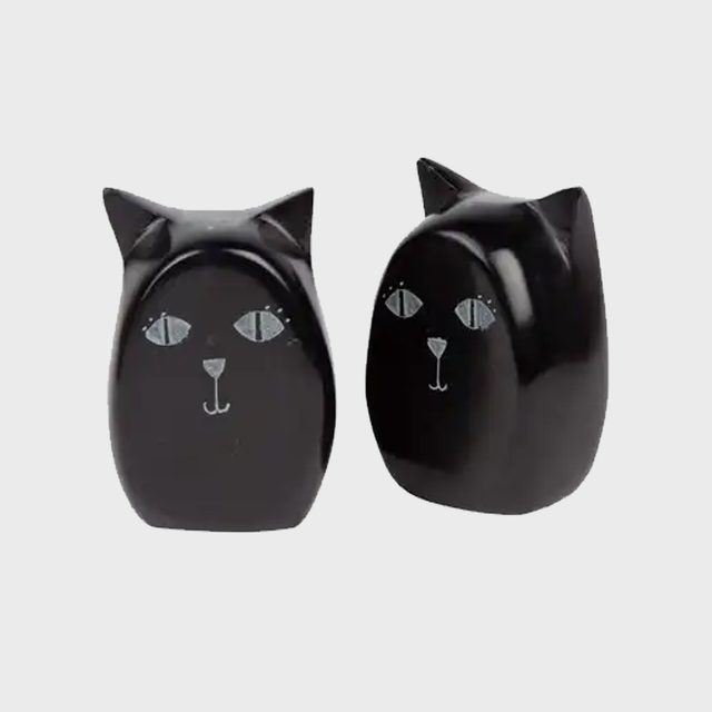 Two black ceramic cat figurines stand side by side, displaying stylized faces, against a plain light gray background.