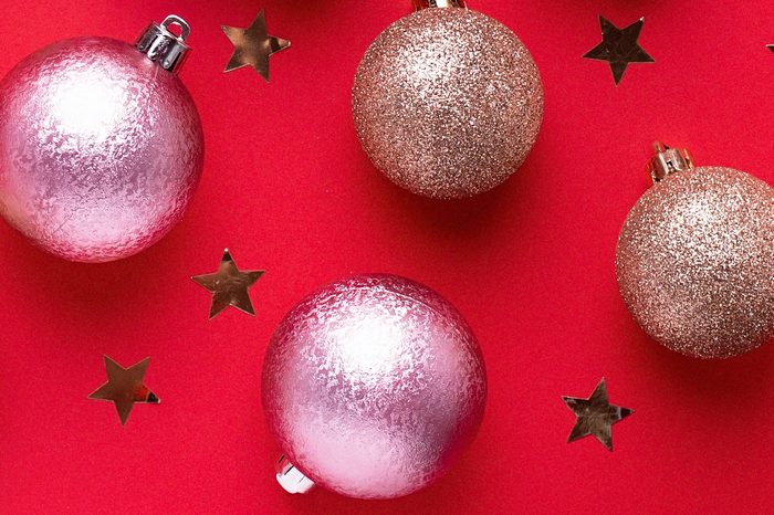 Creative Christmas card with golden balls and wrapped present on red background, copy space, minimalistic lay out