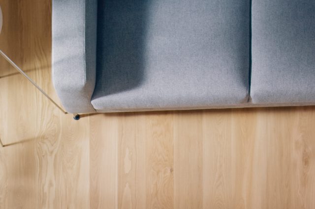 Gray sofa rests on a light wooden floor, with a small round table nearby.