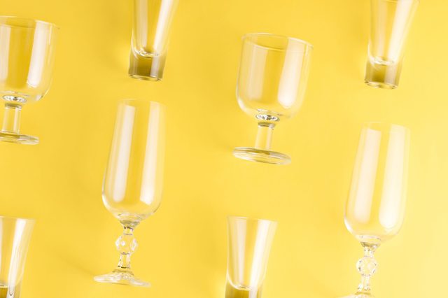 Glassware positioned randomly, tilted on a vibrant yellow background, creating a playful and artistic arrangement.