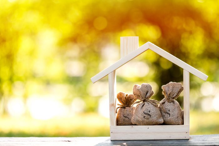 Business loans for real estate concept, a money bags put in a model home on the table on bokeh background in the public park.