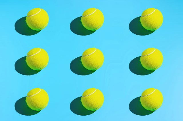 Tennis balls arranged in a grid pattern, casting shadows on a bright blue background.