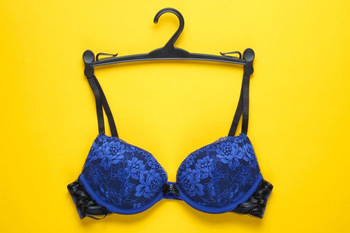 Sexy bra with hanger on yellow background. Top view