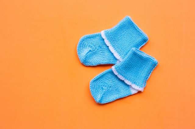 Blue baby socks lie on an orange surface, contrasting brightly.