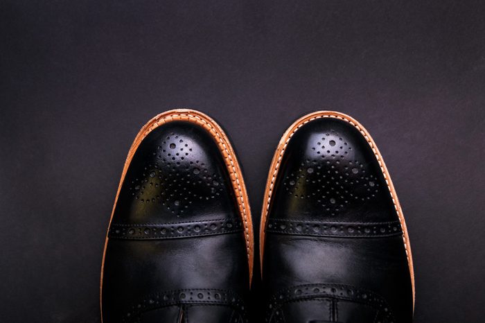 Black shoes with a brown sole on a black background
