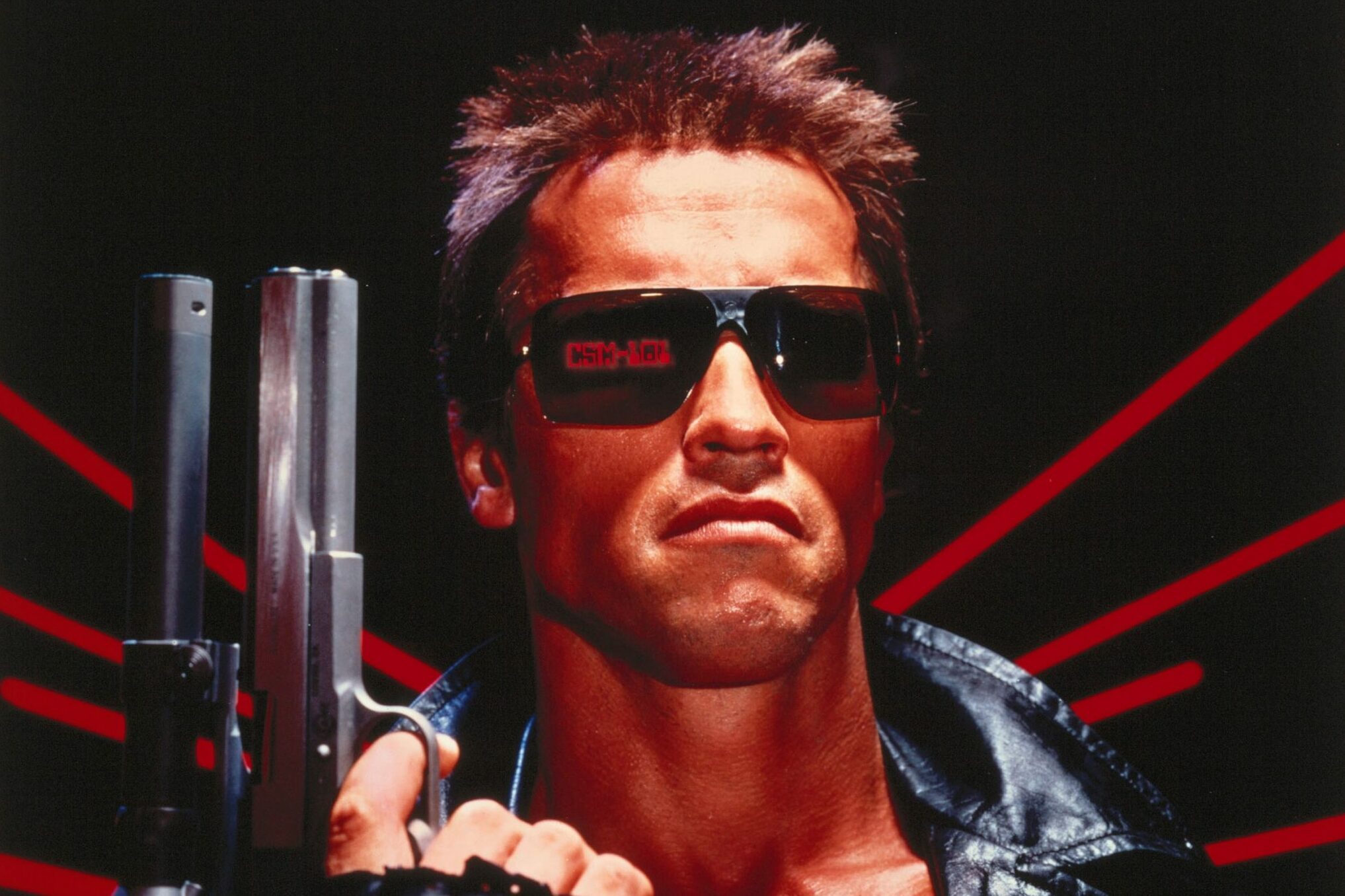 A person holds a large gun, wearing sunglasses with â€œCSM-101â€ reflection; set against a black and red striped backdrop.