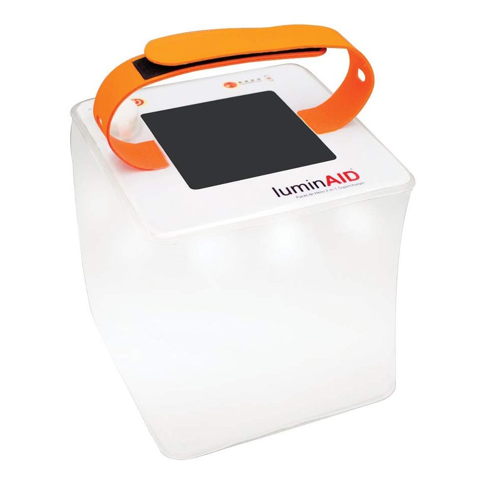 Inflatable lantern displays an orange strap, solar panel, and "luminAID" text on a white cube, suggestive of portable emergency lighting.
