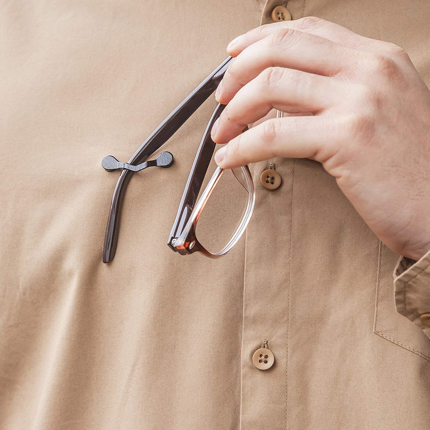 Hand places glasses in holder clipped to a beige shirt, securing them in place.
