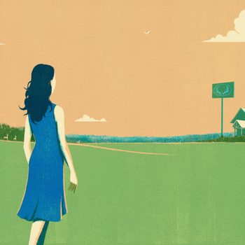 A woman walks across a grassy field toward a distant barn and sign with antlers, under a cloudy sky with birds.