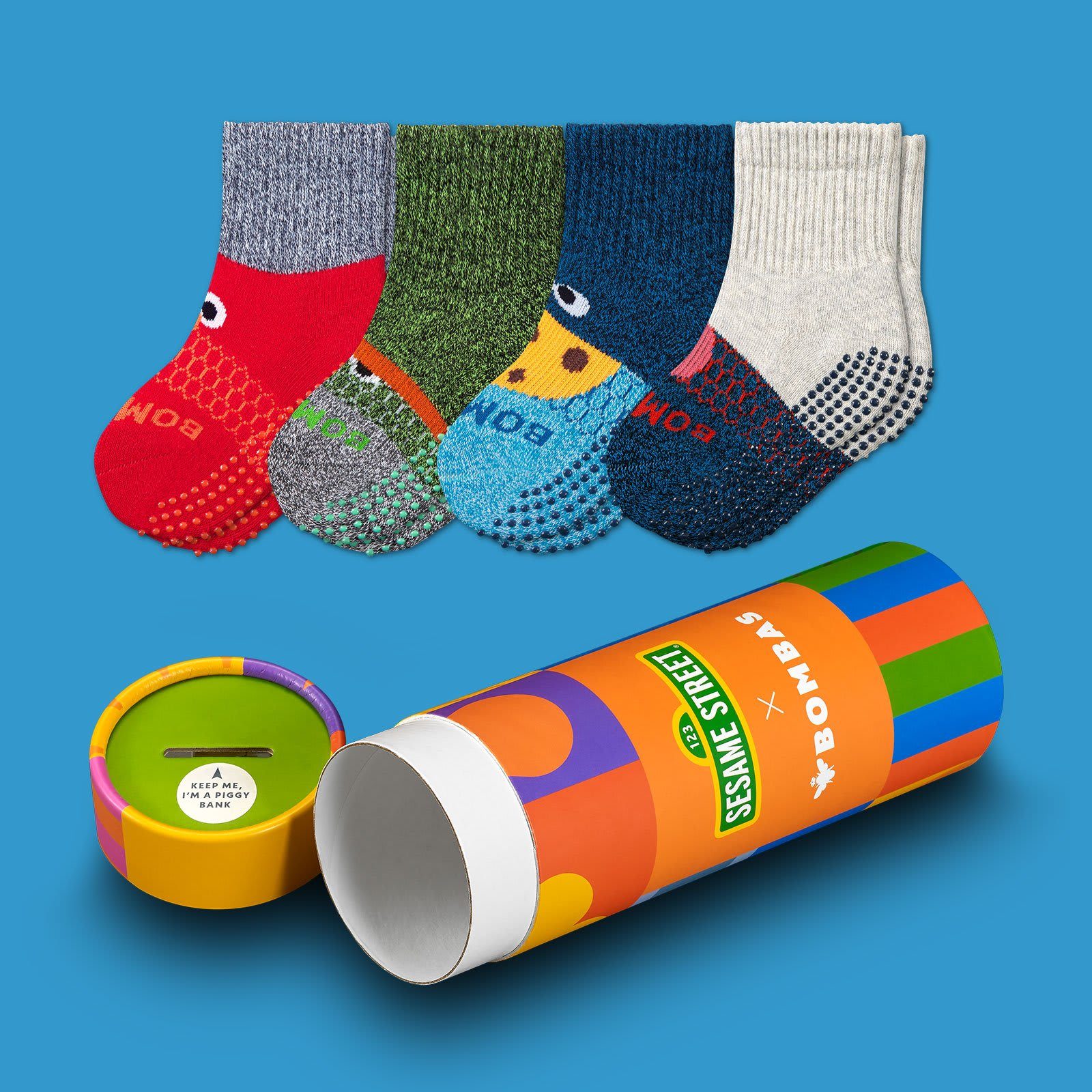 Colorful socks are displayed, hanging together. They're inspired by Sesame Street characters. Nearby, a vibrant cylindrical box labeled "Sesame Street x Bombas" is open.