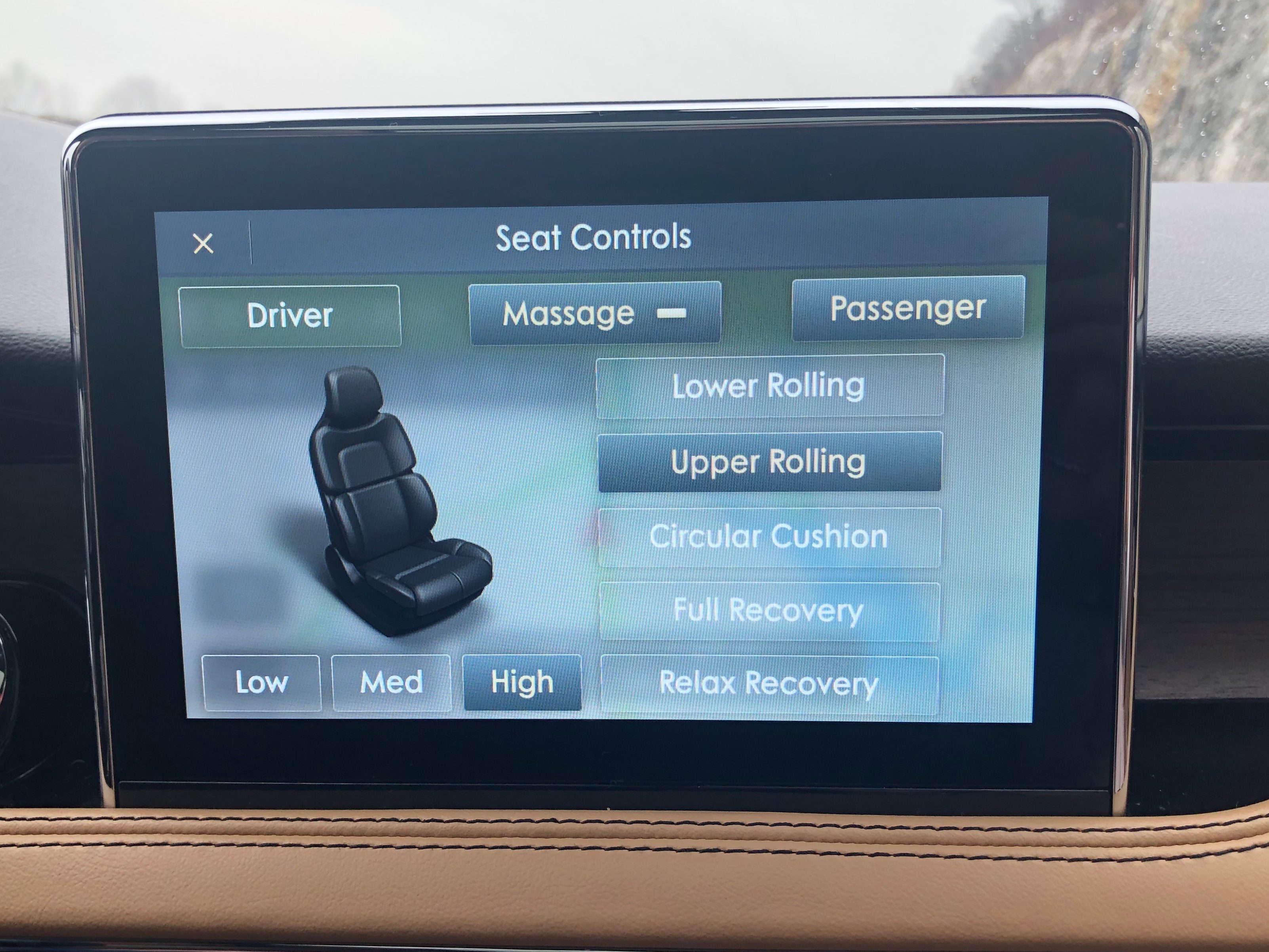 Screen displays car seat controls; options include driver, passenger, massage modes, and intensity (Low, Med, High); situated inside a vehicle interior.