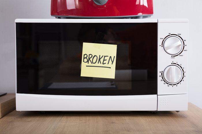 Close-up Of A Microwave Oven With Adhesive Notes Showing Broken Text