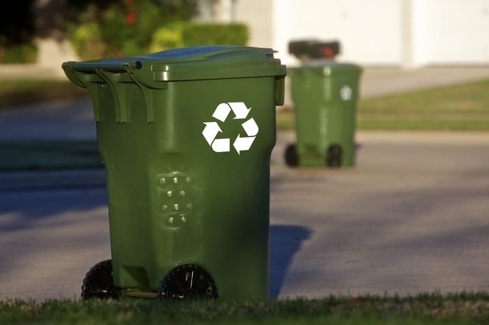 Green recycle bins align a neighborhood street