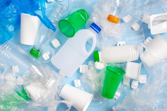 Various plastic garbage on the light blue background, problem of waste sorting and utilisation