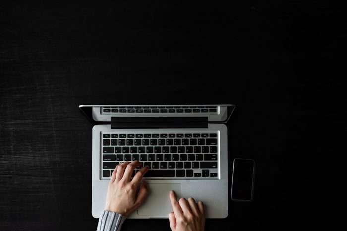 op view of Designer hand working with laptop computer on dark in modern office