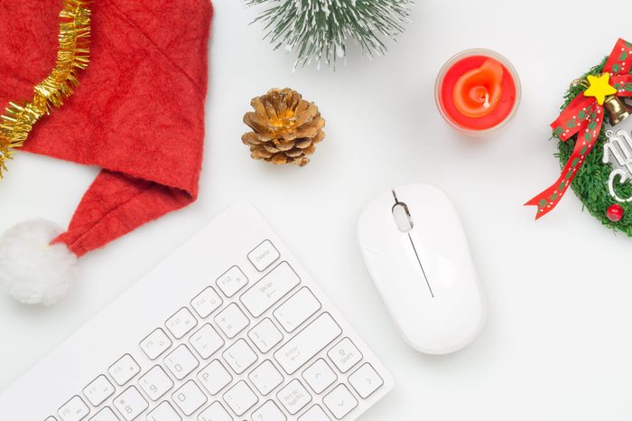 Flat lay top view Christmas office table desk party concept, Christmas workspace with keyboard, Santa Claus hat and Christmas decorations on white background