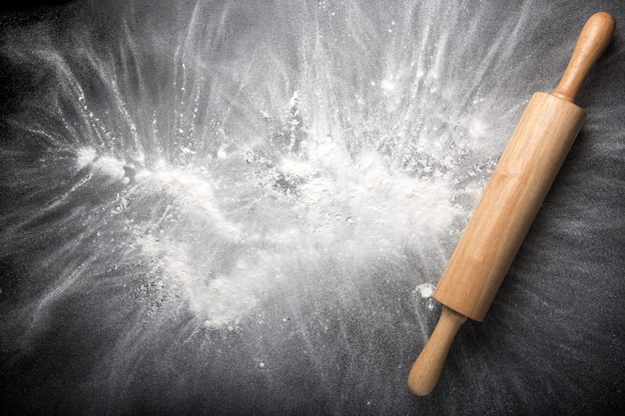 Baking background with the rolling pin with flour. On the dark table. Free space for text . Top view