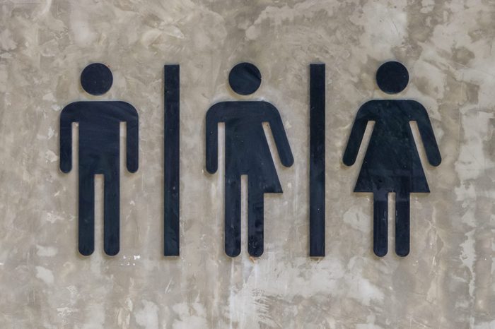 A black symbol stuck on a concrete wall to indicate that it is a toilet.